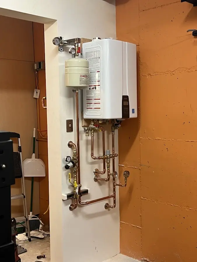 Plumbing technician inspecting water heater connections in Medina